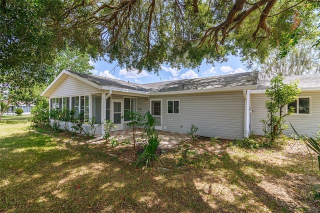 rear view of property with a yard, a patio, and a sunroom