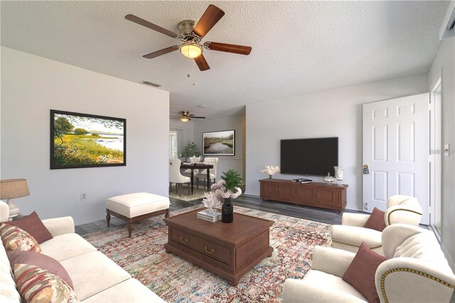 living room featuring a textured ceiling, visible vents, wood finished floors, and a ceiling fan