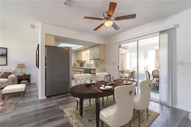 dining room with a textured ceiling, dark wood-style floors, visible vents, and ceiling fan