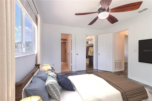 bedroom featuring visible vents, wood finished floors, a walk in closet, and a ceiling fan