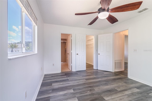 unfurnished bedroom featuring visible vents, wood finished floors, a walk in closet, and a textured ceiling