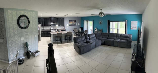 living room featuring a textured ceiling, ceiling fan, and light tile patterned floors