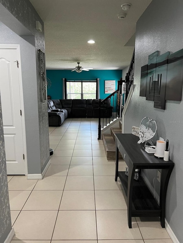 hall with a textured ceiling and light tile floors