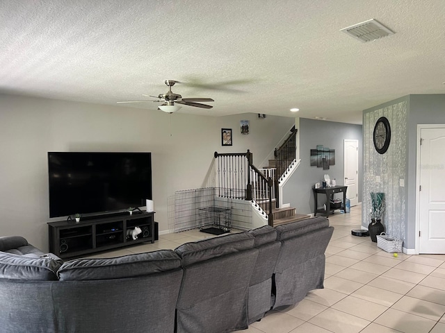 living room featuring ceiling fan, light tile patterned flooring, and a textured ceiling