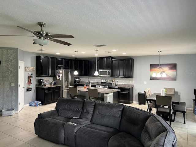 living room featuring ceiling fan, light tile flooring, and a textured ceiling