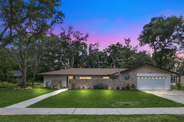 ranch-style house featuring a garage and a yard