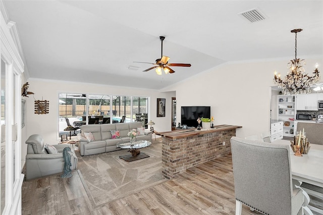 living room featuring vaulted ceiling, ornamental molding, light hardwood / wood-style floors, and ceiling fan with notable chandelier