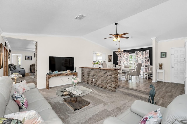 living room with hardwood / wood-style flooring, ornamental molding, lofted ceiling, and ceiling fan with notable chandelier