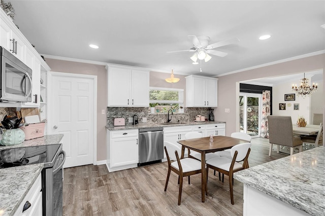 kitchen featuring ceiling fan with notable chandelier, stainless steel appliances, backsplash, light wood-type flooring, and sink