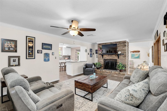 living room with crown molding, ceiling fan, a fireplace, and light hardwood / wood-style flooring