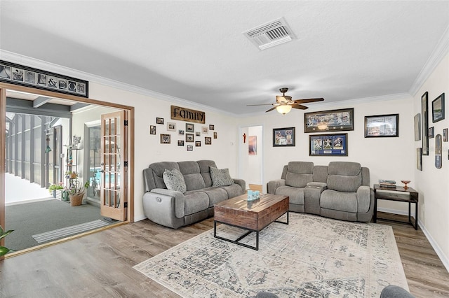 living room featuring hardwood / wood-style flooring, ornamental molding, ceiling fan, and a textured ceiling