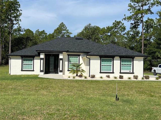 prairie-style house featuring stucco siding, a front yard, and roof with shingles