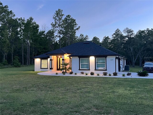 view of front of home featuring cooling unit and a yard