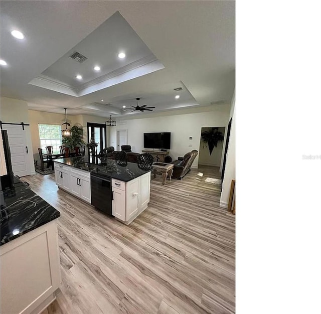 kitchen with white cabinets, a barn door, ceiling fan, a tray ceiling, and light hardwood / wood-style floors