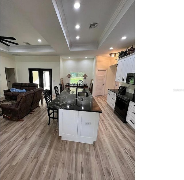 kitchen with light hardwood / wood-style flooring, black appliances, sink, white cabinetry, and a raised ceiling