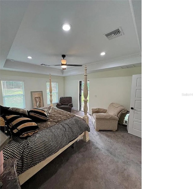 carpeted bedroom with ceiling fan and a raised ceiling