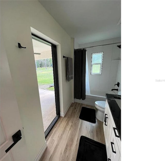 full bath featuring a wealth of natural light, wood finished floors, toilet, and shower / bath combo