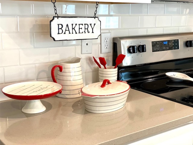 interior details with backsplash and stainless steel range with electric stovetop