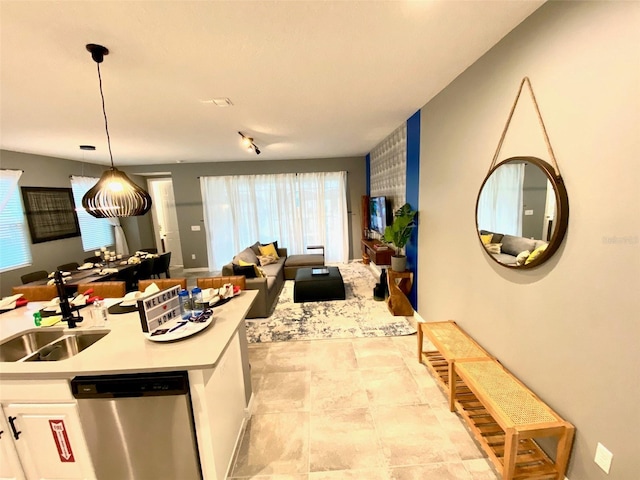 kitchen with dishwasher, white cabinets, pendant lighting, and sink