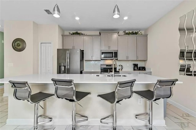 kitchen with gray cabinets, stainless steel appliances, and a large island with sink