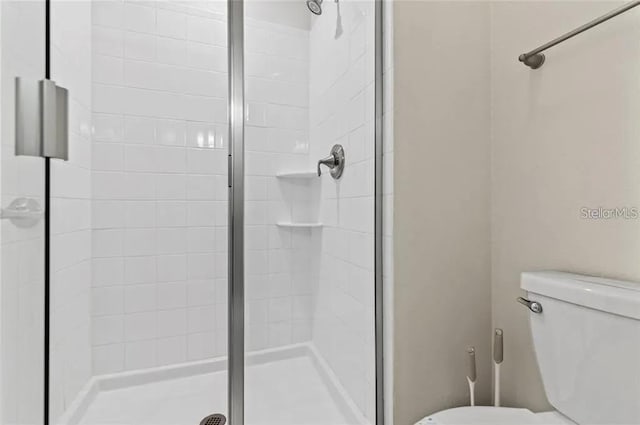 bathroom featuring toilet and a shower with shower door