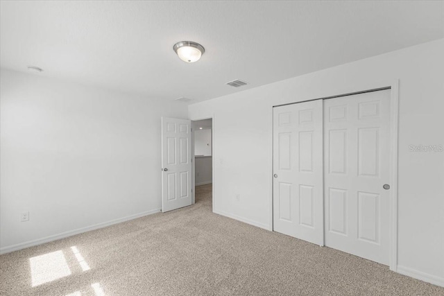 unfurnished bedroom featuring light colored carpet and a closet