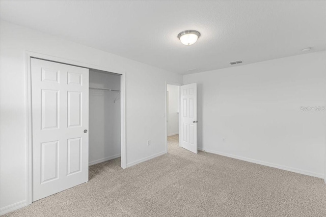 unfurnished bedroom with a closet and light carpet