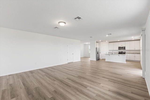 unfurnished living room with light hardwood / wood-style floors and sink