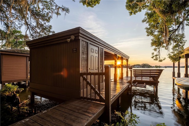 property exterior at dusk featuring a water view and a boat dock