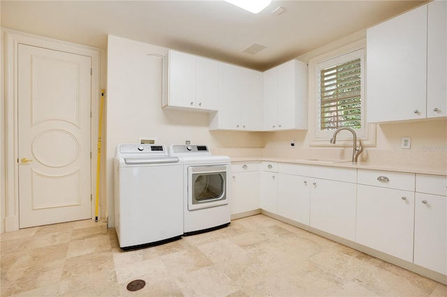 laundry room with sink, washing machine and dryer, and cabinets