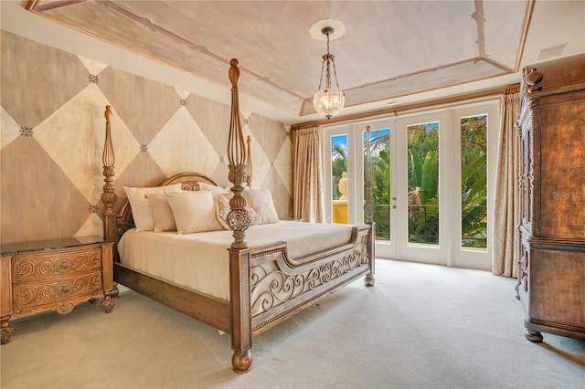 carpeted bedroom with french doors, a tray ceiling, and access to outside