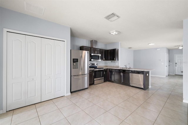 kitchen featuring kitchen peninsula, appliances with stainless steel finishes, light tile patterned floors, and sink