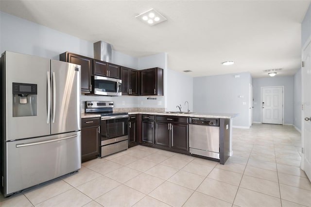 kitchen with appliances with stainless steel finishes, dark brown cabinetry, light tile patterned floors, and sink