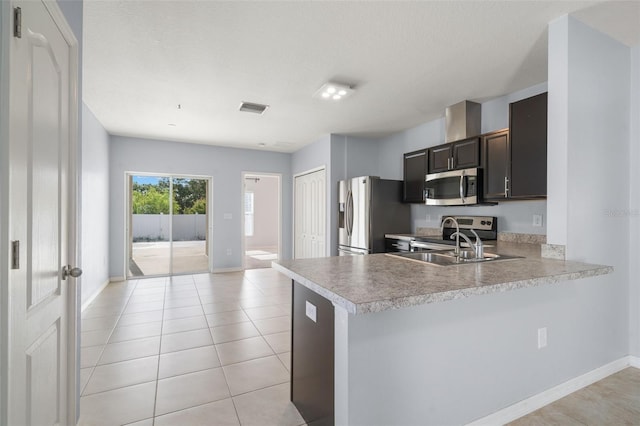 kitchen with kitchen peninsula, dark brown cabinetry, light tile patterned flooring, and stainless steel appliances