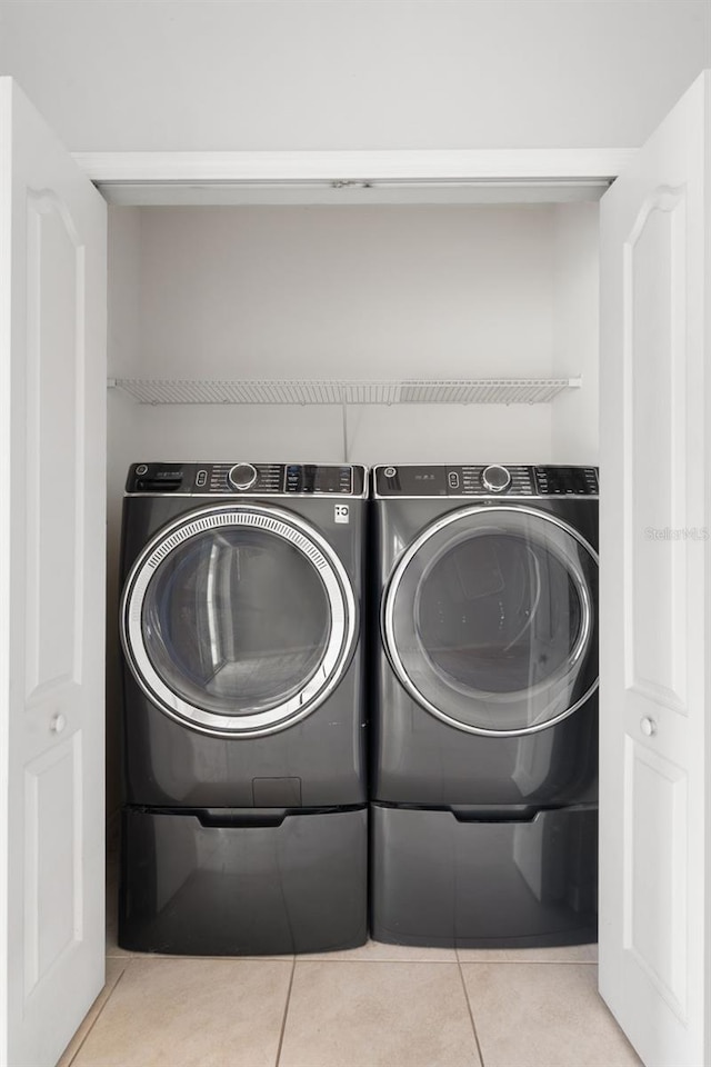 laundry area with washer and clothes dryer and light tile patterned floors