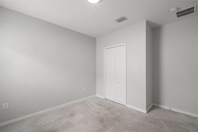 unfurnished bedroom featuring light carpet and a closet