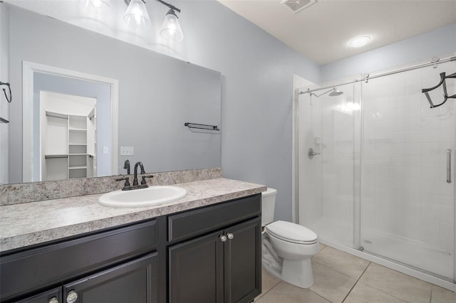 bathroom featuring tile patterned flooring, vanity, a shower with door, and toilet