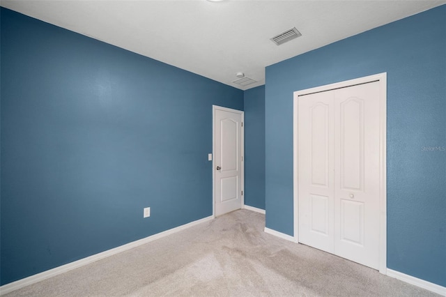 unfurnished bedroom featuring light colored carpet and a closet