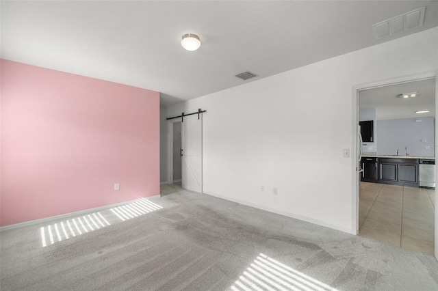 carpeted spare room featuring a barn door and sink