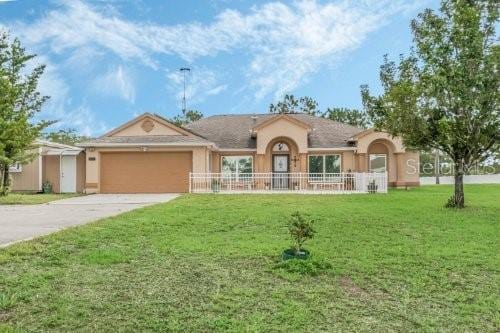 ranch-style home with a garage, a front yard, concrete driveway, and fence