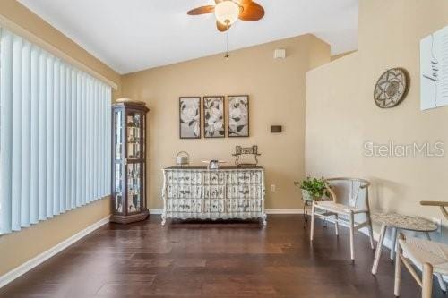 sitting room with dark wood-type flooring, lofted ceiling, ceiling fan, and baseboards