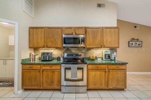 kitchen with stainless steel appliances, dark countertops, backsplash, and visible vents