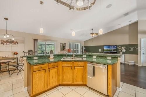 kitchen with a kitchen island with sink, a sink, and stainless steel dishwasher