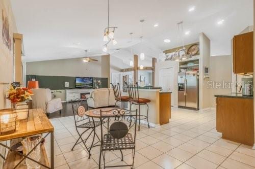 kitchen featuring stainless steel fridge, lofted ceiling, ceiling fan, open floor plan, and decorative light fixtures