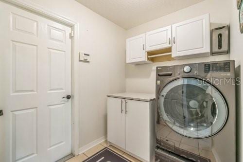 laundry room featuring cabinet space, baseboards, washer / clothes dryer, and light tile patterned flooring