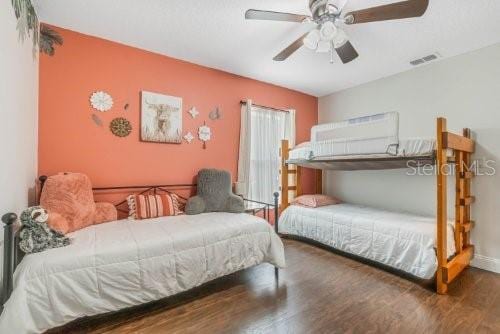 bedroom featuring ceiling fan, dark wood-type flooring, visible vents, and baseboards