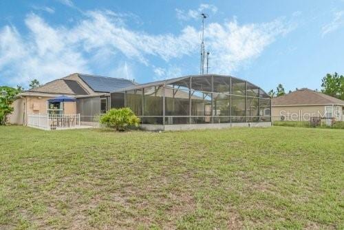 rear view of property featuring a lanai and a yard