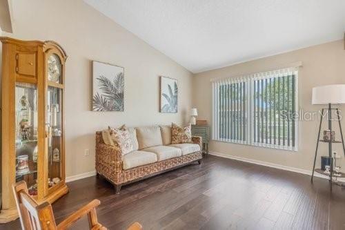 sitting room featuring lofted ceiling, baseboards, and dark wood-style flooring