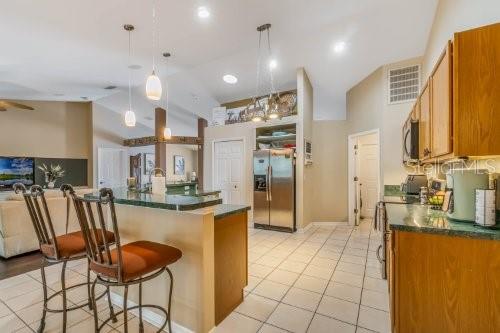 kitchen with brown cabinets, stainless steel appliances, dark countertops, visible vents, and a kitchen island