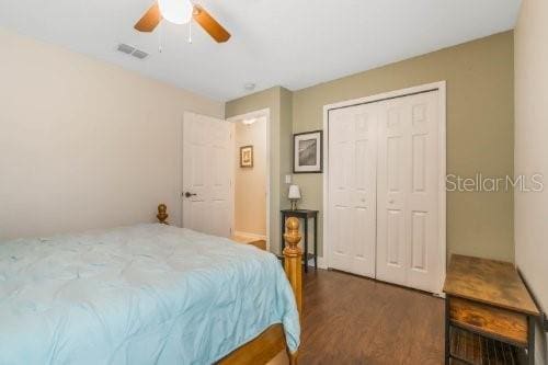 bedroom featuring a closet, dark wood finished floors, visible vents, and a ceiling fan